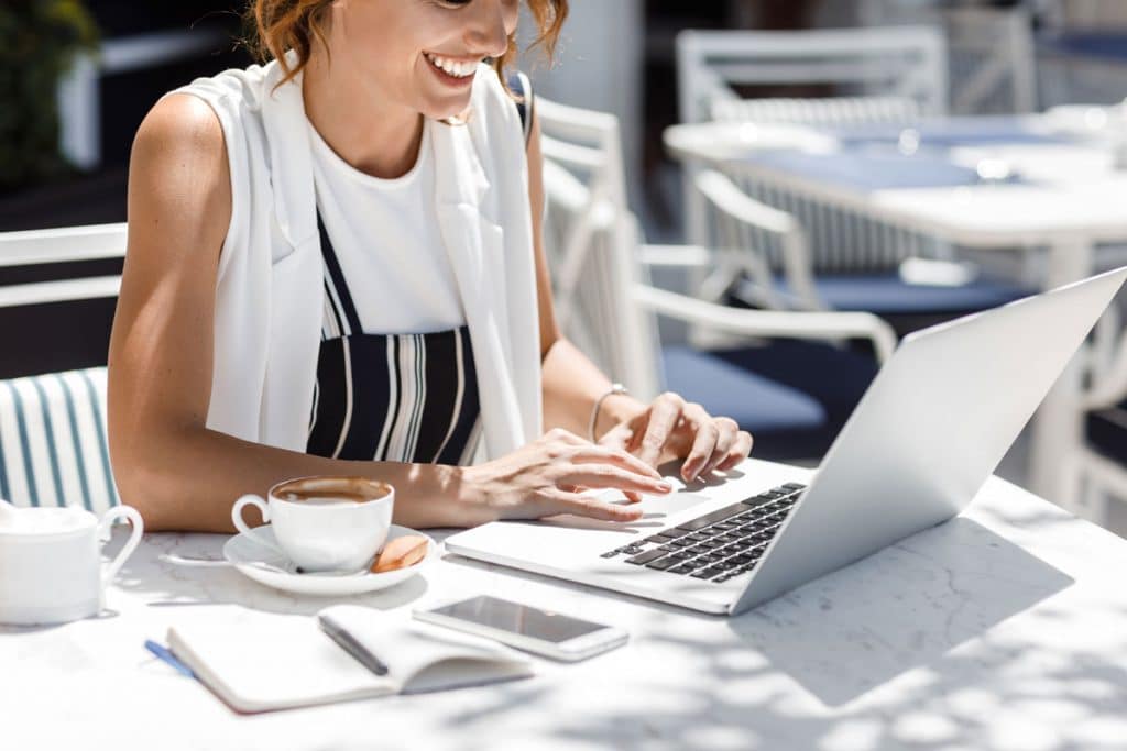 Woman working on a laptop at an outdoor cafe table