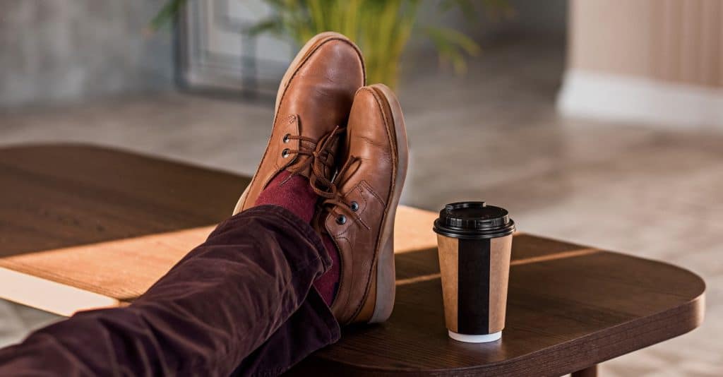 Feet up on a table next to a takeaway coffee